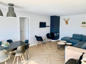 a living room with a blue couch and a table and chairs at Chalet a estrenar, espectaculares vistas a la montaña in Torremocha de Jarama