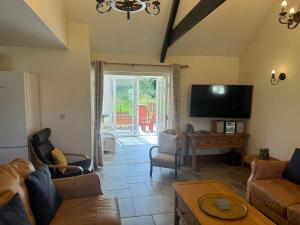 a living room with a couch and a flat screen tv at Plas Drygarn Ty Coch Crymych in Crymych