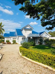a white house with blue roofs and a gravel driveway at We Call it Home - Bububu Villa in Mtoni