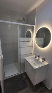 a white bathroom with a shower and a sink at Le Royal, proche Paris & Disney in Noisy-le-Grand +2 photos