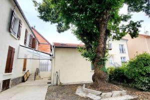 a tree in front of a building with a garage at Le Royal, proche Paris & Disney in Noisy-le-Grand