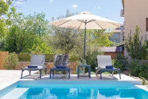 two chairs and an umbrella next to a swimming pool at Villa Marin in Klimno