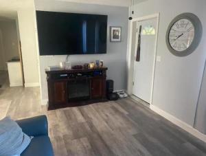 a living room with a tv and a clock on the wall at North Hill Cottage in Pensacola