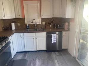 a kitchen with white cabinets and a stainless steel dishwasher at North Hill Cottage in Pensacola