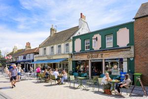 a group of people sitting at tables on a street at Modern Seaside Townhouse feat Sauna near Brighton in Shoreham-by-Sea