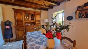 a dining room table with a vase with flowers on it at Les Chambres du Saladou in Mont-Chanson