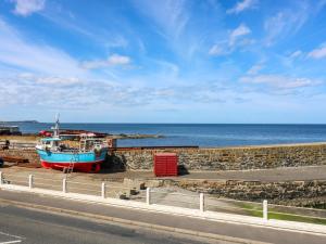 a boat sitting on the sand near the ocean at West Pier Cottage in Macduff