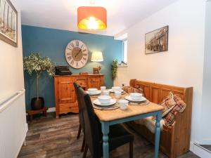 a dining room with a table and a clock on the wall at West Pier Cottage in Macduff
