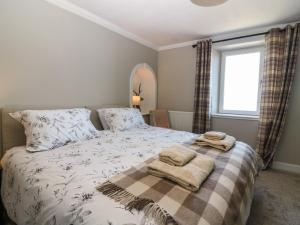 a bedroom with a bed with two towels on it at West Pier Cottage in Macduff