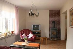 a living room with a red chair and a fireplace at Ferienwohnungen auf dem Lande in Kittendorf +9 photos