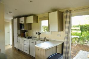a kitchen with white cabinets and a sink and a window at Gezellig vakantiechalet in bosrijke omgeving op de Veluwe in Epe +23 photos