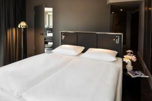 a bedroom with a large white bed with two pillows at Hotel ROMY by AMANO in Berlin