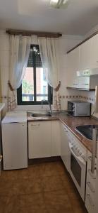 a kitchen with white cabinets and a sink and a window at Apartamento Cozy Inns Beach in Torremolinos