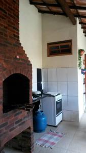 a kitchen with a brick fireplace and a stove at Pousada Melodia do Mar in Cabo Frio