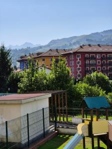 a playground with a slide and buildings in the background at Jardines del Sella in Cangas de Onís
