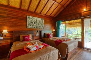 two beds in a room with wooden walls at Ayu Hill Bungalows in Nusa Penida