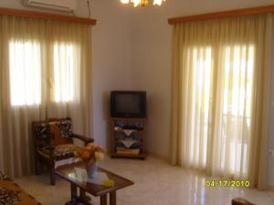a living room with a tv and a table at Elisabeth Villas in Kerveli