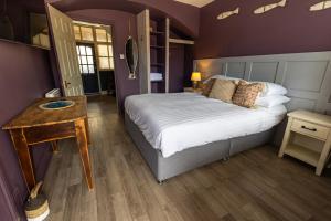 a purple bedroom with a bed and a wooden floor at Harbour Way Cottage by Coast & Country Stays in Seahouses