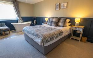 a bedroom with a large bed and a bath tub at Harbour Way Cottage by Coast & Country Stays in Seahouses
