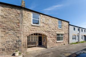 an old stone building with a large door at Harbour Way Cottage by Coast & Country Stays in Seahouses