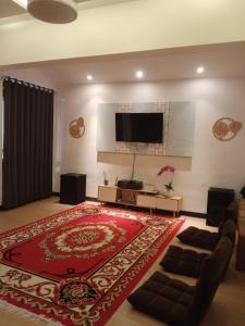 - un salon avec un tapis rouge et une télévision à écran plat dans l'établissement Villa de Voltaf, à Pasirputih