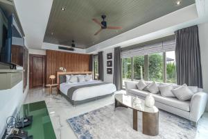 a bedroom with a bed and a living room at Baan Phu Prana Boutique Villa in Surin Beach