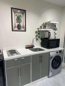 a kitchen with a sink and a washing machine at Duba gold in Ḑubā