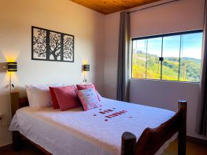 a bedroom with a bed with a large window at Chalé Vista do Paraíso in Gonçalves