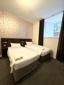 two beds in a small room with a window at Murrayfield Park Guest House in Edinburgh