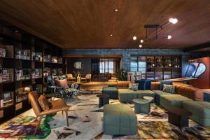 ニューヨークにあるMoxy NYC East Villageのソファ、椅子、本棚が備わる図書室
