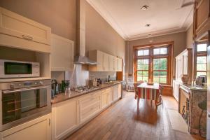 a large kitchen with white cabinets and a table at Manoir de la Dune in Quend