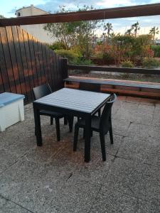 a picnic table and two chairs on a patio at T2 cabine en rdj grande terrasse et garage 3 min de la plage in Cap d'Agde