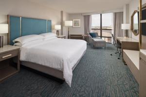 a hotel room with a large bed and a desk at Sheraton Dallas Hotel by the Galleria in Dallas