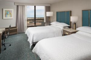 a hotel room with two beds and a desk at Sheraton Dallas Hotel by the Galleria in Dallas