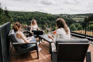 three women sitting around a table on a balcony at UplandParcs Sauerland in Winterberg