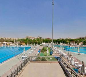 a large swimming pool with umbrellas and chairs and water at Comfy Relaxing Home in Madinaty in Madinaty