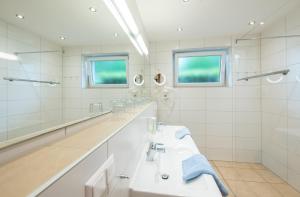 a white bathroom with two sinks and mirrors at Barry Memle Directly at the Lake in Velden am Wörthersee