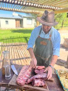 a man in a hat preparing meat on a table at Estancia Palma in Tupungato +26 photos