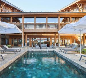 a pool with chairs and umbrellas next to a building at Pirin Golf Guest Room in Razlog