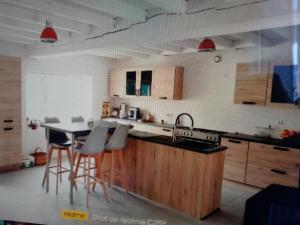 Saint-Hilaire-le-VouhisにあるChambre à la campagneのシンクとバースツール付きのテーブルを備えたキッチン