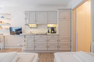 a white kitchen with white cabinets and a sink at fewo1846 Intermar - Gruene Insel - Studioapartment mit Balkon und Blick ins Grüne in Glücksburg