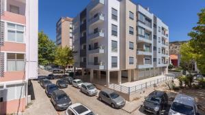 an apartment building with cars parked in a parking lot at Seaside Getaway With Balcony by LovelyStay in Almada