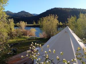 a white tent in a field next to a river at Snake River Glamping in Irwin