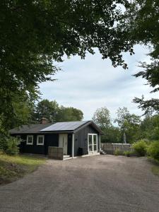 a small black building with a large driveway at Cozy Retreat with Modern Charm in Hjärnarp