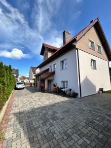 a large white house with a brick driveway at Dom Gościnny Stokrotka in Pustkowo