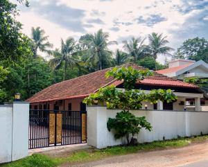 a house with a black gate and a white fence at Glanwoods Inn - 2BHK Independent Private house in Mangalore - Pets allowed in Mangalore