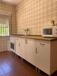 a kitchen with white cabinets and a microwave at villa eloisa in Chiclana de la Frontera