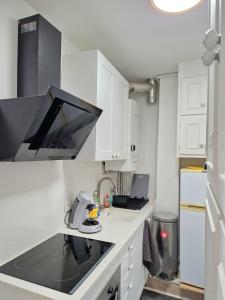 a kitchen with white cabinets and a black counter top at Cosy 2 pièces proche de Paris avec parking in Gentilly
