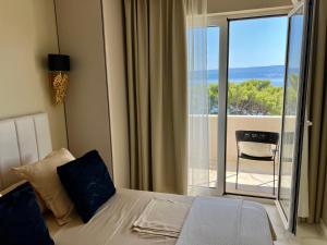 a bedroom with a bed and a view of a balcony at LIZA I Sea View in Lokva Rogoznica