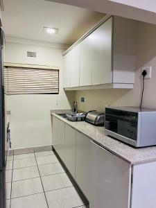 a kitchen with white cabinets and a microwave at Banana Beach Club Unit A2 in Port Shepstone